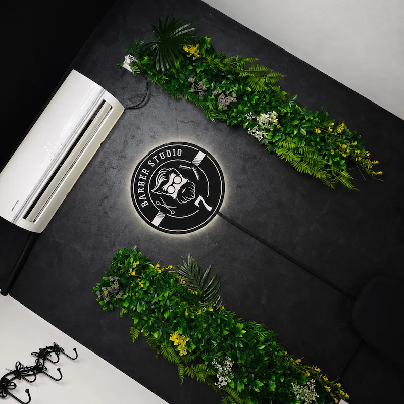 Zidni logo Barber Studio 7 u Nišu na crnom zidu sa zelenom dekoracijom